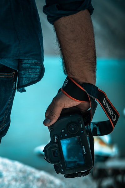 Holding a black Canon SLR cameras
